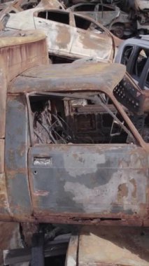 Bu stok dikey video Irpin, Bucha bölgesinde gri, düz, renksiz, yanmış arabaları gösteriyor.