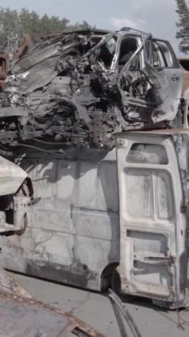Bu stok dikey video Irpin, Bucha bölgesinde gri, düz, renksiz, yanmış arabaları gösteriyor.