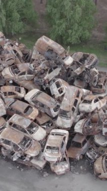 Bu stok dikey video Irpin, Bucha bölgesinde gri, düz, renksiz, yanmış arabaları gösteriyor.