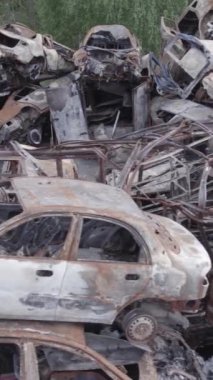 Bu stok dikey video Irpin, Bucha bölgesinde gri, düz, renksiz, yanmış arabaları gösteriyor.