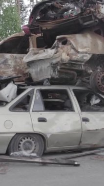 Bu stok dikey video Irpin, Bucha bölgesinde gri, düz, renksiz, yanmış arabaları gösteriyor.
