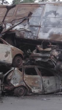 Bu stok dikey video Irpin, Bucha bölgesinde gri, düz, renksiz, yanmış arabaları gösteriyor.