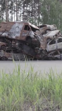 Bu stok dikey video Irpin, Bucha bölgesinde gri, düz, renksiz, yanmış arabaları gösteriyor.