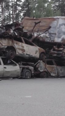 Bu stok dikey video Irpin, Bucha bölgesinde gri, düz, renksiz, yanmış arabaları gösteriyor.