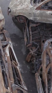 Bu stok dikey video Irpin, Bucha bölgesinde gri, düz, renksiz, yanmış arabaları gösteriyor.