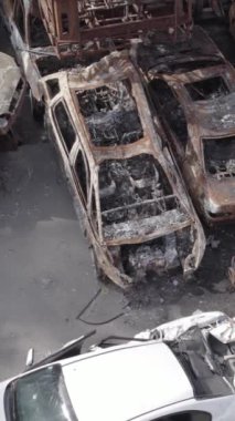 Bu stok dikey video Irpin, Bucha bölgesinde gri, düz, renksiz, yanmış arabaları gösteriyor.