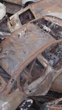 Bu stok dikey video Irpin, Bucha bölgesinde gri, düz, renksiz, yanmış arabaları gösteriyor.