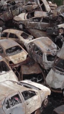 Bu stok dikey video Irpin, Bucha bölgesinde gri, düz, renksiz, yanmış arabaları gösteriyor.