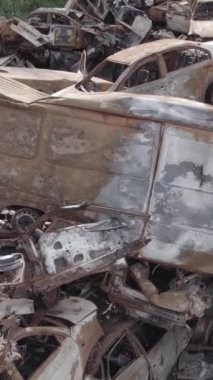 Bu stok dikey video Irpin, Bucha bölgesinde gri, düz, renksiz, yanmış arabaları gösteriyor.
