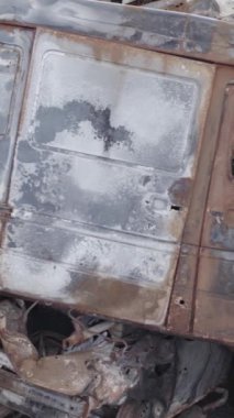 Bu stok dikey video Irpin, Bucha bölgesinde gri, düz, renksiz, yanmış arabaları gösteriyor.