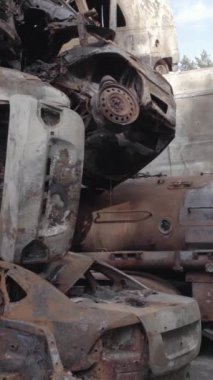 Bu stok dikey video Irpin, Bucha bölgesinde gri, düz, renksiz, yanmış arabaları gösteriyor.