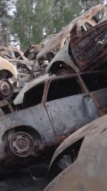 Bu stok dikey video Irpin, Bucha bölgesinde gri, düz, renksiz, yanmış arabaları gösteriyor.