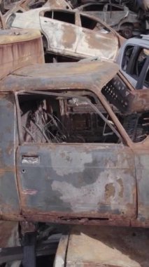 Bu stok dikey video Irpin, Bucha bölgesinde gri, düz, renksiz, yanmış arabaları gösteriyor.