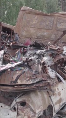 Bu stok dikey video Irpin, Bucha bölgesinde gri, düz, renksiz, yanmış arabaları gösteriyor.