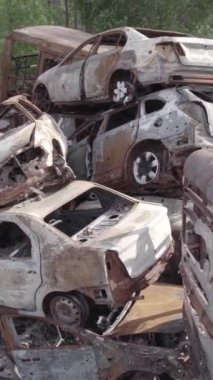 Bu stok dikey video Irpin, Bucha bölgesinde gri, düz, renksiz, yanmış arabaları gösteriyor.