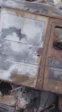 Bu stok dikey video Irpin, Bucha bölgesinde gri, düz, renksiz, yanmış arabaları gösteriyor.