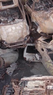 Bu stok dikey video Irpin, Bucha bölgesinde gri, düz, renksiz, yanmış arabaları gösteriyor.