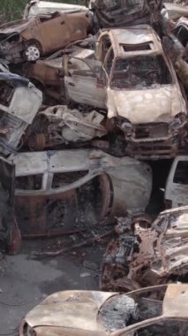 Bu stok dikey video Irpin, Bucha bölgesinde gri, düz, renksiz, yanmış arabaları gösteriyor.