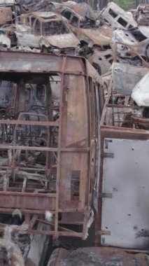 Bu stok dikey video Irpin, Bucha bölgesinde gri, düz, renksiz, yanmış arabaları gösteriyor.
