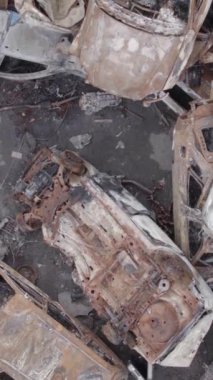 Bu stok dikey video Irpin, Bucha bölgesinde gri, düz, renksiz, yanmış arabaları gösteriyor.