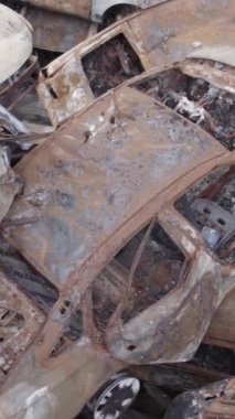 Bu stok dikey video Irpin, Bucha bölgesinde gri, düz, renksiz, yanmış arabaları gösteriyor.