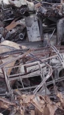 Bu stok dikey video Irpin, Bucha bölgesinde gri, düz, renksiz, yanmış arabaları gösteriyor.