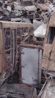 Bu stok dikey video Irpin, Bucha bölgesinde gri, düz, renksiz, yanmış arabaları gösteriyor.