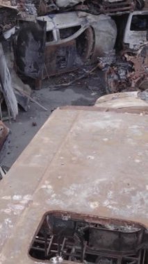 Bu stok dikey video Irpin, Bucha bölgesinde gri, düz, renksiz, yanmış arabaları gösteriyor.