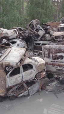 Bu stok dikey video Irpin, Bucha bölgesinde gri, düz, renksiz, yanmış arabaları gösteriyor.