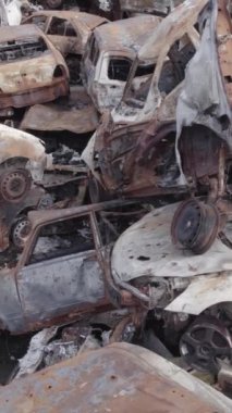 Bu stok dikey video Irpin, Bucha bölgesinde gri, düz, renksiz, yanmış arabaları gösteriyor.