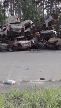 Bu stok dikey video Irpin, Bucha bölgesinde gri, düz, renksiz, yanmış arabaları gösteriyor.