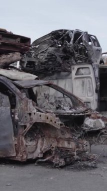 Bu stok dikey video Irpin, Bucha bölgesinde gri, düz, renksiz, yanmış arabaları gösteriyor.