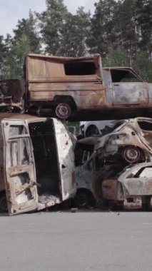 Bu stok dikey video Irpin, Bucha bölgesinde gri, düz, renksiz, yanmış arabaları gösteriyor.