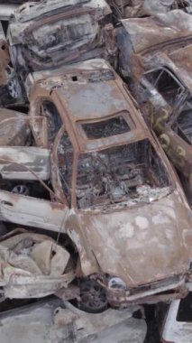 Bu stok dikey video Irpin, Bucha bölgesinde gri, düz, renksiz, yanmış arabaları gösteriyor.