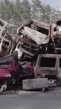 Bu stok dikey video Irpin, Bucha bölgesinde gri, düz, renksiz, yanmış arabaları gösteriyor.
