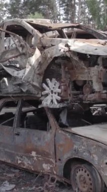 Bu stok dikey video Irpin, Bucha bölgesinde gri, düz, renksiz, yanmış arabaları gösteriyor.