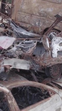 Bu stok dikey video Irpin, Bucha bölgesinde gri, düz, renksiz, yanmış arabaları gösteriyor.