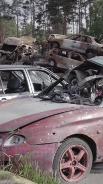 Bu stok dikey video Irpin, Bucha bölgesinde gri, düz, renksiz, yanmış arabaları gösteriyor.