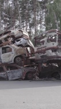 Bu stok dikey video Irpin, Bucha bölgesinde gri, düz, renksiz, yanmış arabaları gösteriyor.