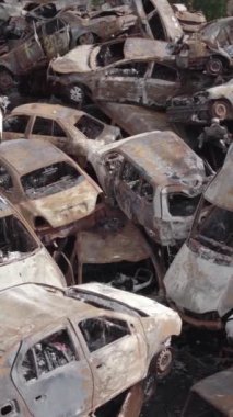 Bu stok dikey video Irpin, Bucha bölgesinde gri, düz, renksiz, yanmış arabaları gösteriyor.