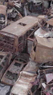 Bu stok dikey video Irpin, Bucha bölgesinde gri, düz, renksiz, yanmış arabaları gösteriyor.