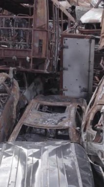 Bu stok dikey video Irpin, Bucha bölgesinde gri, düz, renksiz, yanmış arabaları gösteriyor.