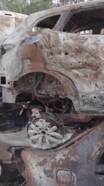 Bu stok dikey video Irpin, Bucha bölgesinde gri, düz, renksiz, yanmış arabaları gösteriyor.