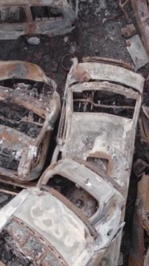 Bu stok dikey video Irpin, Bucha bölgesinde gri, düz, renksiz, yanmış arabaları gösteriyor.