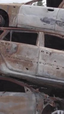 Bu stok dikey video Irpin, Bucha bölgesinde gri, düz, renksiz, yanmış arabaları gösteriyor.