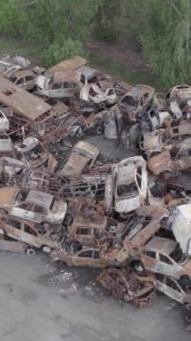 Bu stok dikey video Irpin, Bucha bölgesinde gri, düz, renksiz, yanmış arabaları gösteriyor.