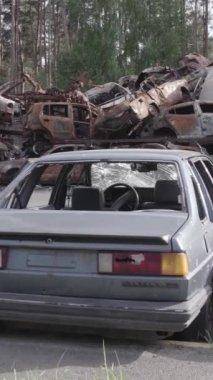 Bu stok dikey video Irpin, Bucha bölgesinde gri, düz, renksiz, yanmış arabaları gösteriyor.