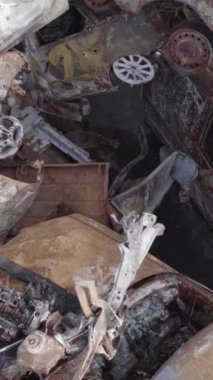 Bu stok dikey video Irpin, Bucha bölgesinde gri, düz, renksiz, yanmış arabaları gösteriyor.