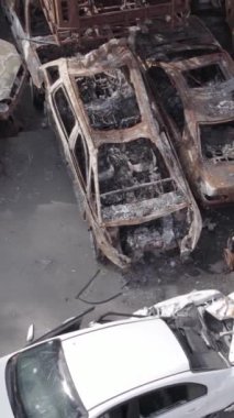 Bu stok dikey video Irpin, Bucha bölgesinde gri, düz, renksiz, yanmış arabaları gösteriyor.