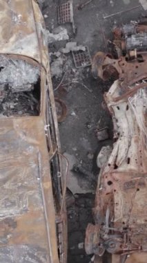 Bu stok dikey video Irpin, Bucha bölgesinde gri, düz, renksiz, yanmış arabaları gösteriyor.